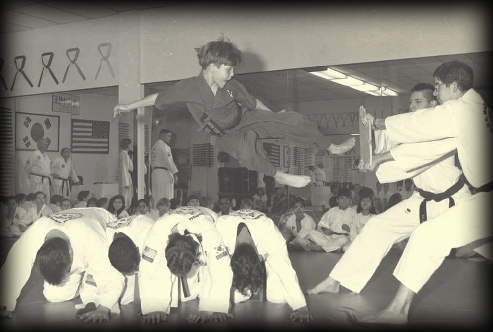 Student does Flying Side Kick Over 4 people to break a board